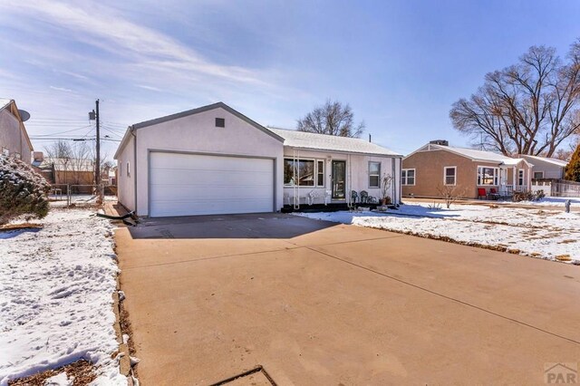 view of front of home with concrete driveway, an attached garage, and stucco siding