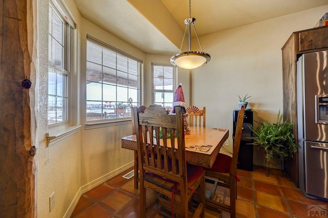 dining space with dark tile patterned floors and baseboards