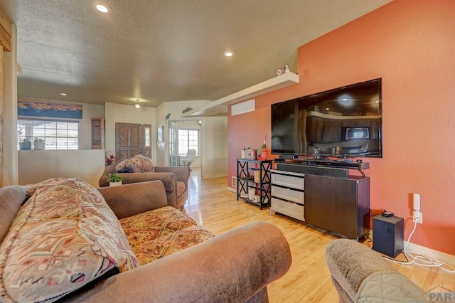 living room with light wood finished floors, recessed lighting, visible vents, a textured ceiling, and baseboards