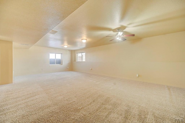 spare room featuring carpet floors, visible vents, ceiling fan, and a textured ceiling