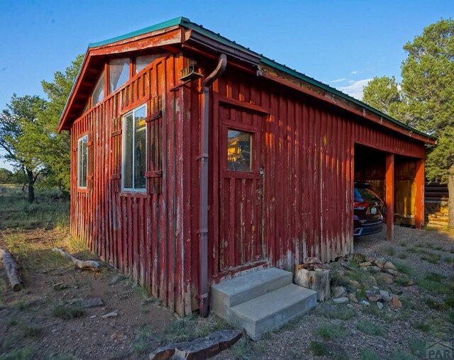 view of property exterior featuring entry steps, metal roof, and an outbuilding