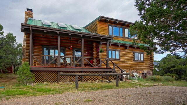 rear view of house with a chimney, metal roof, and log exterior