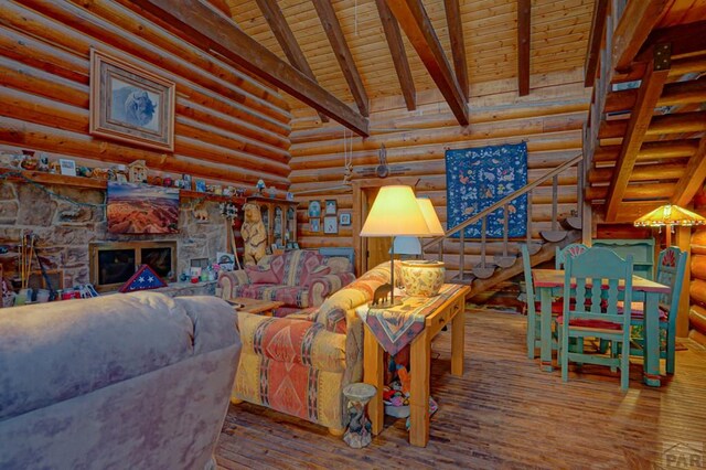 living area featuring a fireplace, log walls, lofted ceiling with beams, wood finished floors, and wooden ceiling