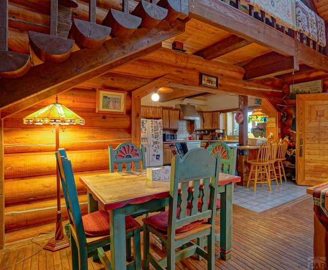 dining area featuring light wood-style flooring, log walls, and lofted ceiling with beams