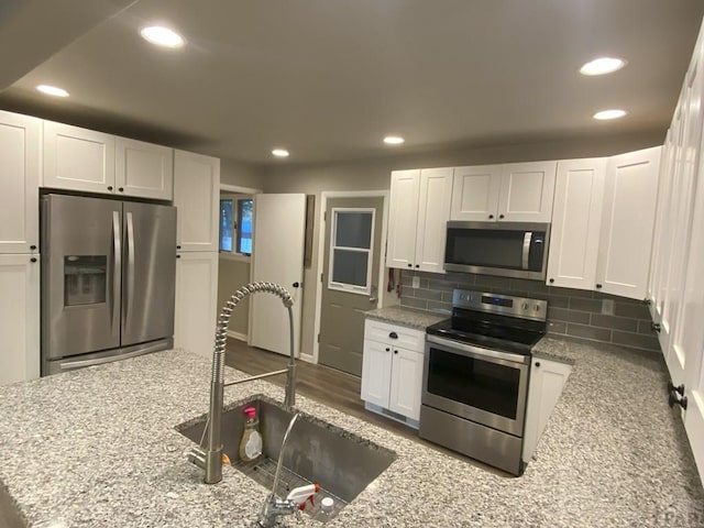kitchen featuring stainless steel appliances, recessed lighting, white cabinetry, and a sink