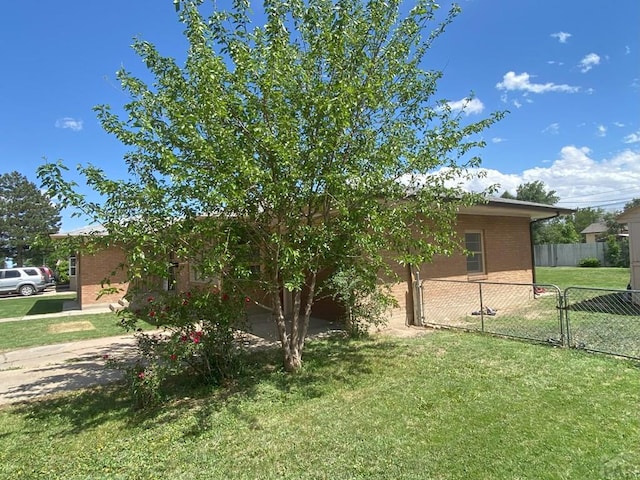 exterior space featuring fence, a yard, and brick siding
