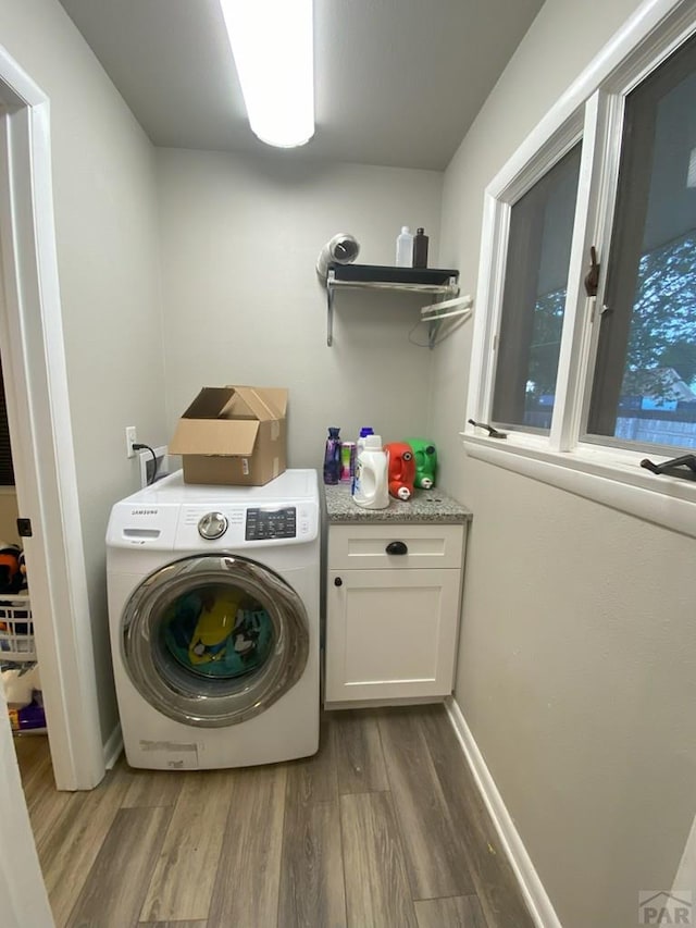 laundry area with cabinet space, baseboards, washer / dryer, and wood finished floors