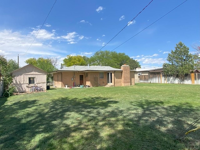rear view of house with fence, a yard, and a chimney
