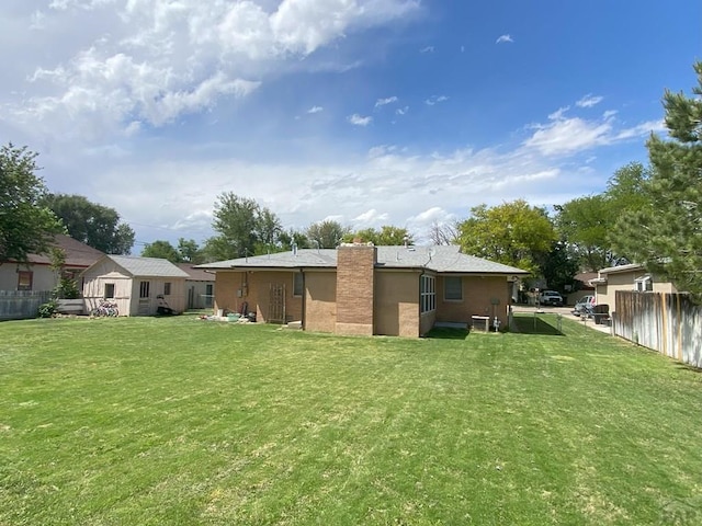 back of house featuring a yard, fence, and a chimney