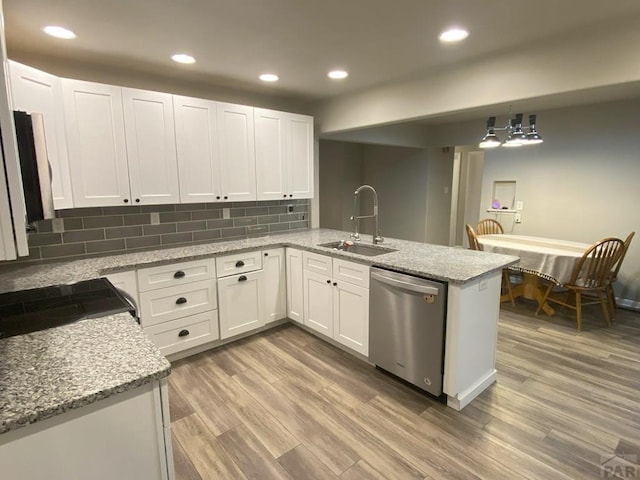 kitchen featuring a sink, light wood-type flooring, a peninsula, and dishwasher