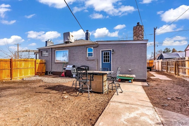 back of property featuring a fenced backyard, brick siding, a chimney, and exterior bar