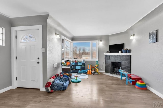 foyer entrance featuring a fireplace, baseboards, wood finished floors, and a textured wall