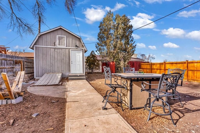 view of patio featuring a fenced backyard, a storage unit, outdoor dry bar, and an outdoor structure