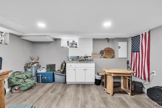 interior space with light wood-style floors, light countertops, white cabinetry, and a sink