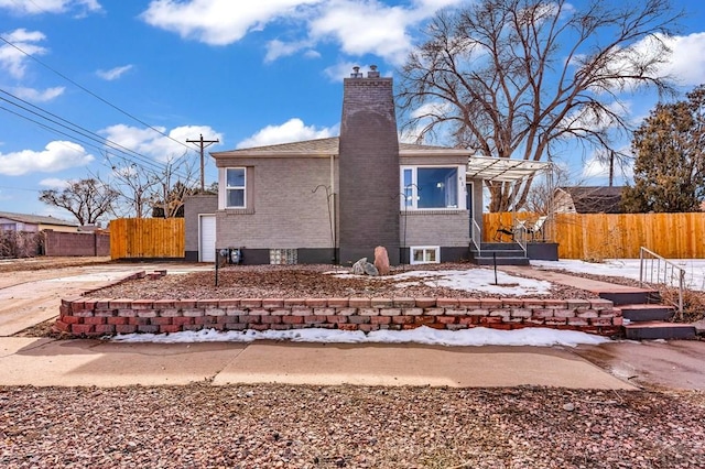 back of house featuring brick siding, a chimney, fence, and a pergola