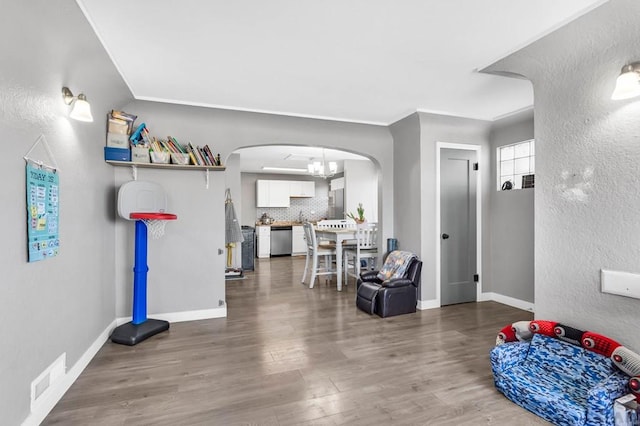 interior space with baseboards, visible vents, arched walkways, and wood finished floors