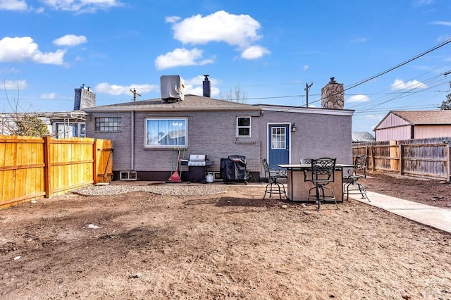 rear view of house featuring a fenced backyard and brick siding