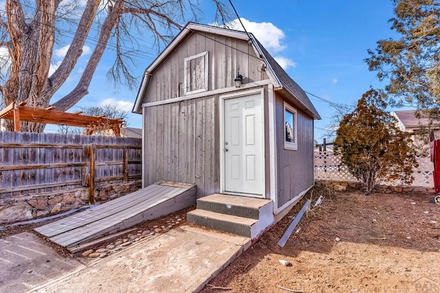 view of outbuilding featuring fence and an outdoor structure