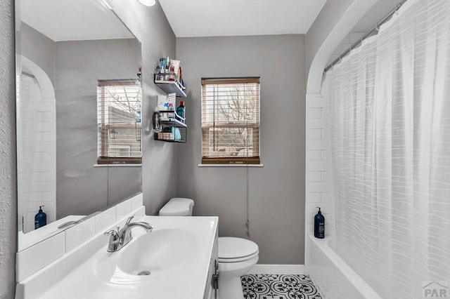 bathroom with a wealth of natural light, baseboards, vanity, and toilet