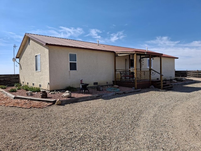 exterior space with crawl space, fence, metal roof, and stucco siding