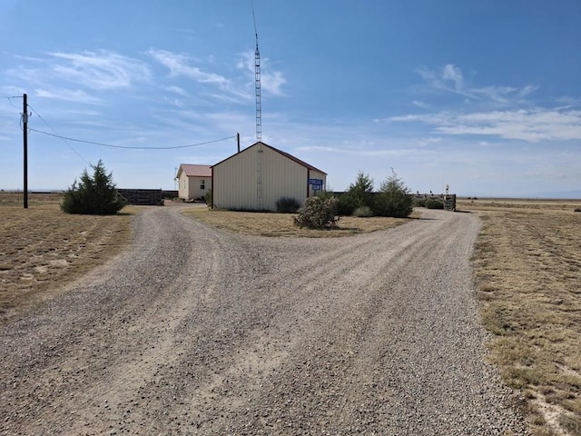 view of street with gravel driveway and a rural view