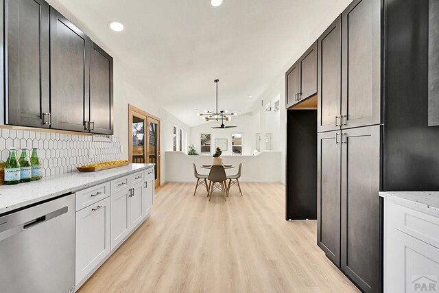 kitchen featuring vaulted ceiling, a chandelier, decorative backsplash, stainless steel dishwasher, and light wood-style floors