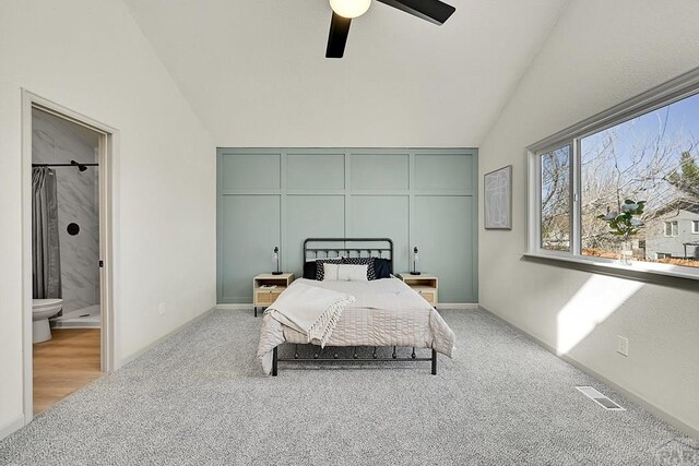bedroom featuring ensuite bathroom, carpet flooring, visible vents, ceiling fan, and vaulted ceiling