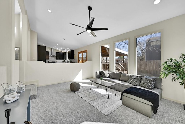carpeted living room with ceiling fan with notable chandelier, baseboards, and recessed lighting