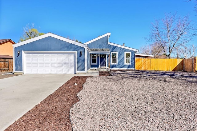 view of front facade featuring driveway, a garage, and fence