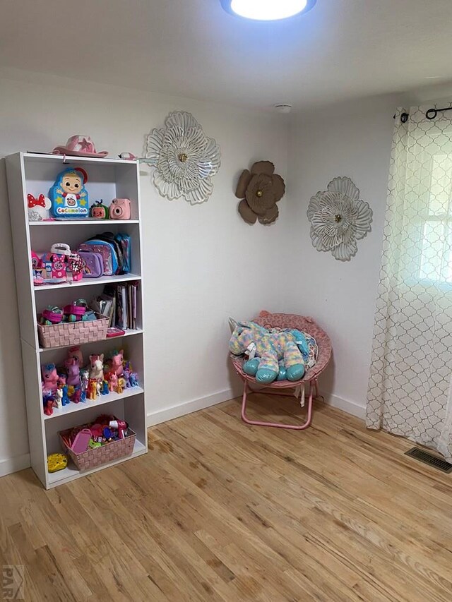 recreation room with light wood finished floors, visible vents, and baseboards