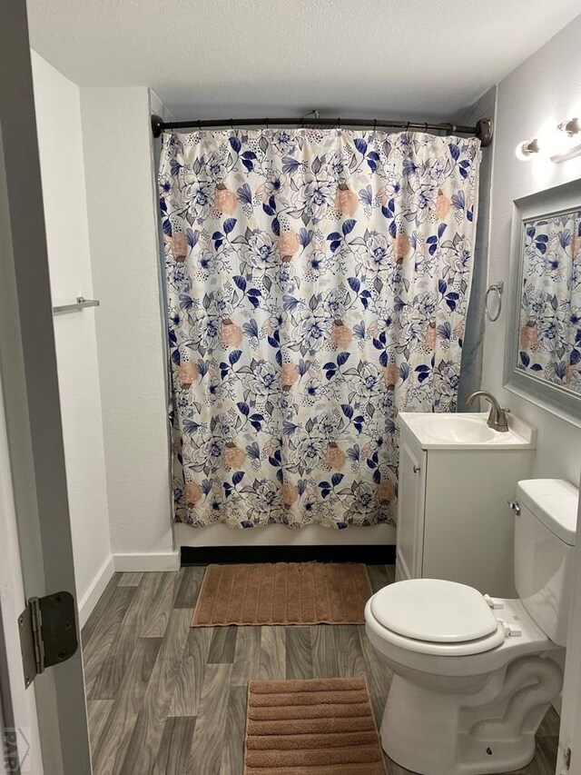 full bathroom featuring toilet, vanity, wood finished floors, a shower with curtain, and baseboards