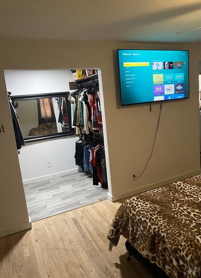 bedroom with light wood finished floors, a ceiling fan, baseboards, and a closet