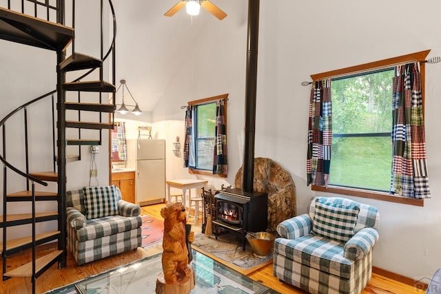 living area featuring a wood stove, ceiling fan, light wood-style flooring, and stairs