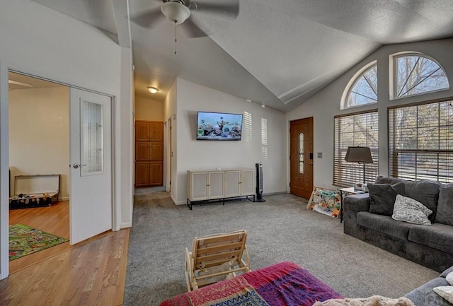 living room featuring baseboards, a ceiling fan, a textured ceiling, light wood-type flooring, and high vaulted ceiling