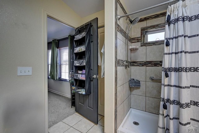 bathroom featuring tile patterned flooring, a shower stall, and baseboards