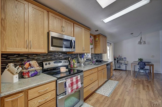 kitchen featuring stainless steel appliances, light wood-style floors, light countertops, and pendant lighting
