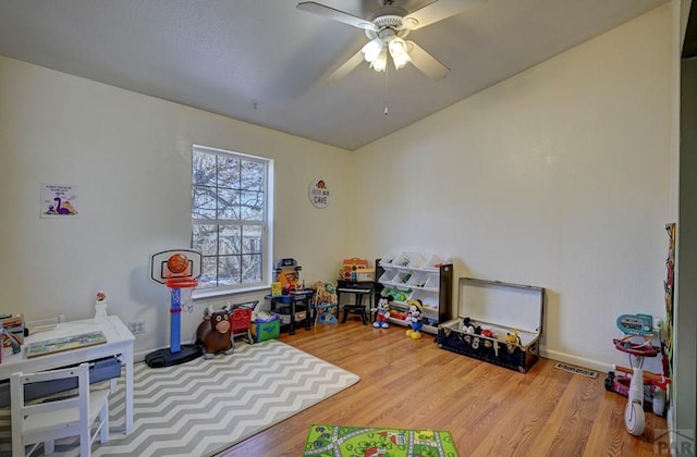 rec room with baseboards, wood finished floors, visible vents, and a ceiling fan