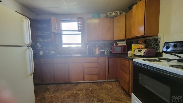 kitchen featuring freestanding refrigerator, brown cabinetry, a sink, range with electric cooktop, and backsplash