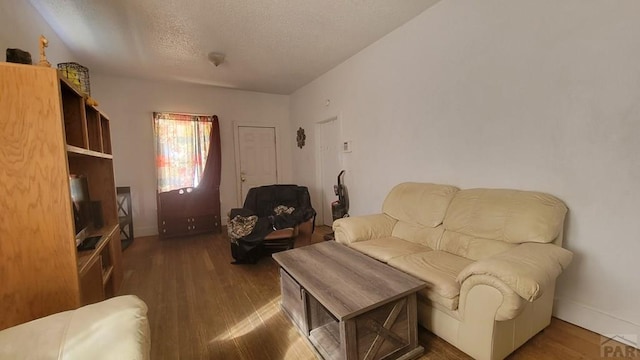 living room featuring a textured ceiling, wood finished floors, and baseboards