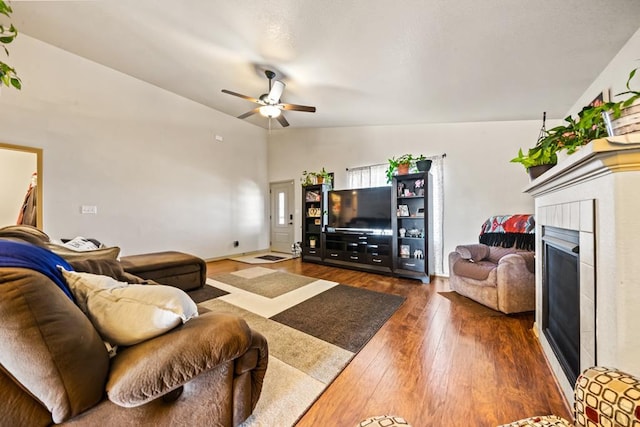 living area featuring dark wood-style floors, lofted ceiling, a fireplace, and ceiling fan