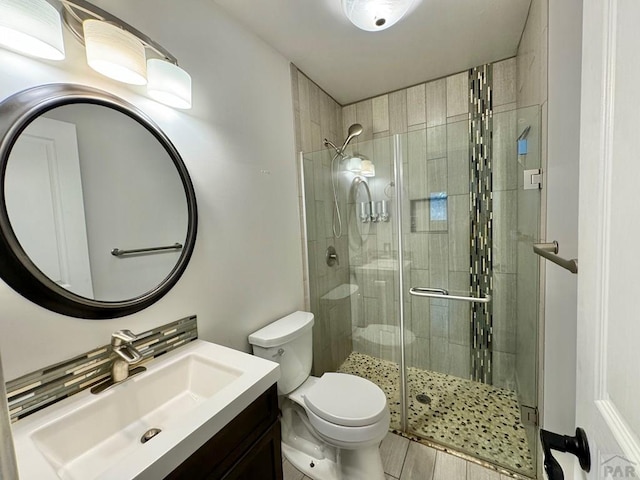 bathroom with toilet, a stall shower, and vanity