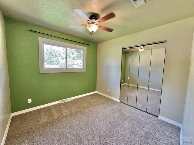 unfurnished bedroom featuring carpet flooring, visible vents, baseboards, and a textured ceiling