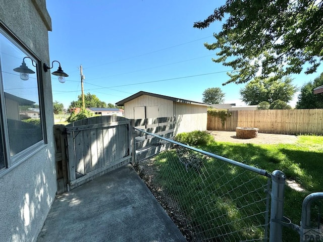 view of yard with a gate, fence, and a fire pit