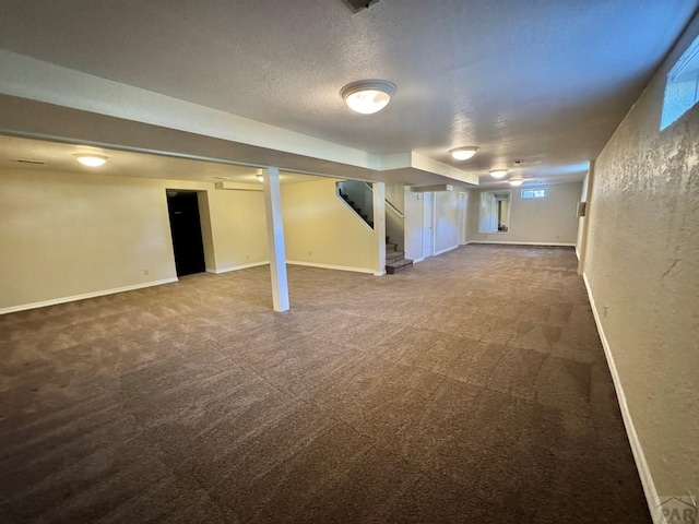 finished below grade area featuring carpet, stairs, baseboards, and a textured ceiling