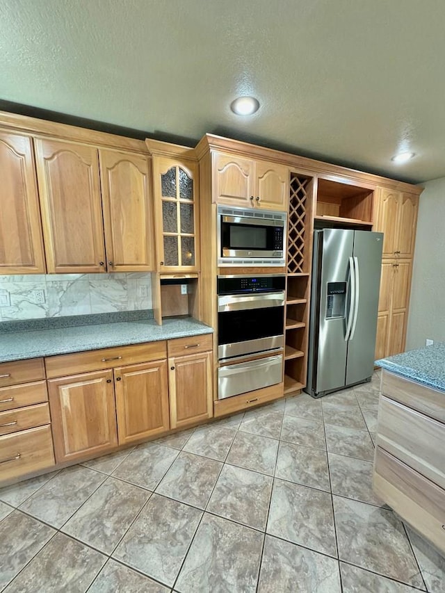 kitchen with recessed lighting, light countertops, appliances with stainless steel finishes, decorative backsplash, and a warming drawer