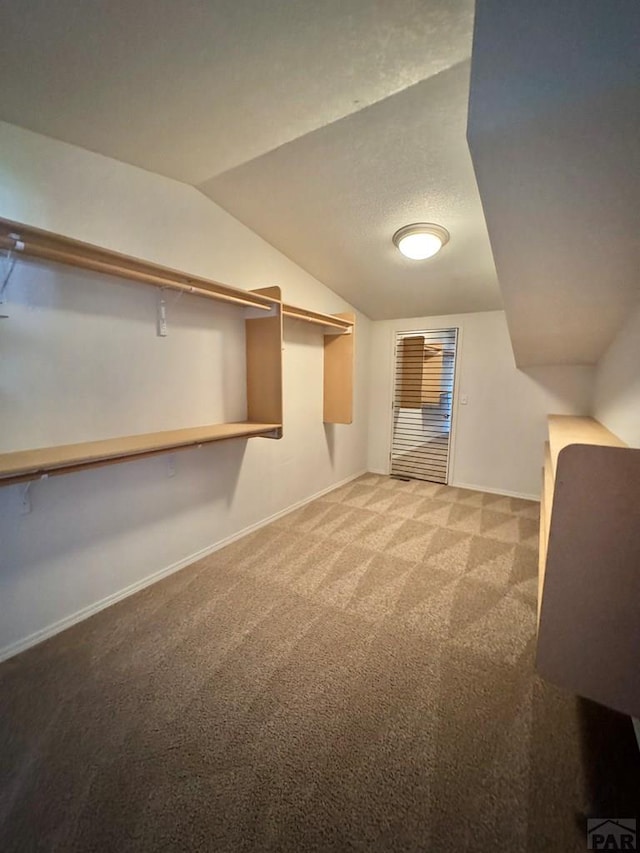 walk in closet with carpet floors and lofted ceiling