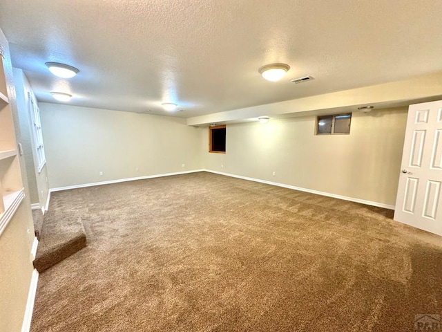 finished below grade area featuring carpet flooring, a textured ceiling, and baseboards