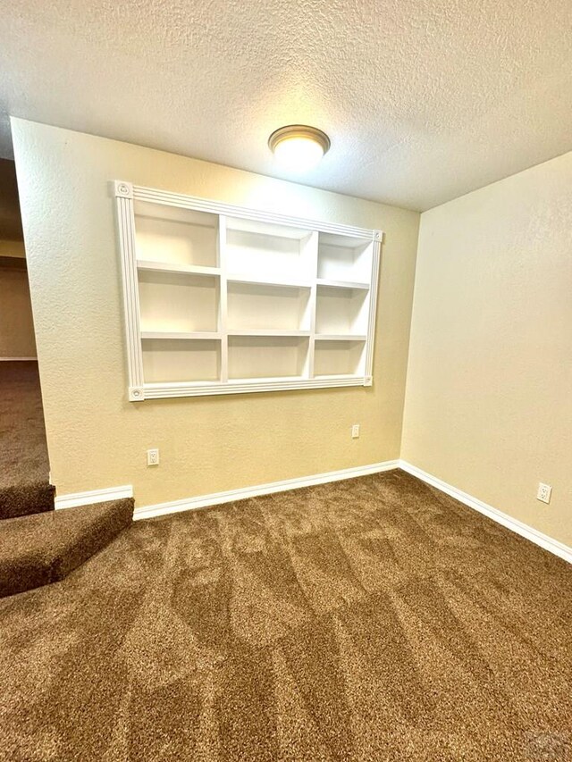 unfurnished room featuring a textured ceiling, carpet floors, and baseboards