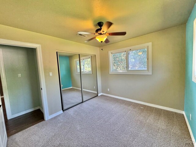 unfurnished bedroom featuring a closet, visible vents, carpet flooring, a textured ceiling, and baseboards