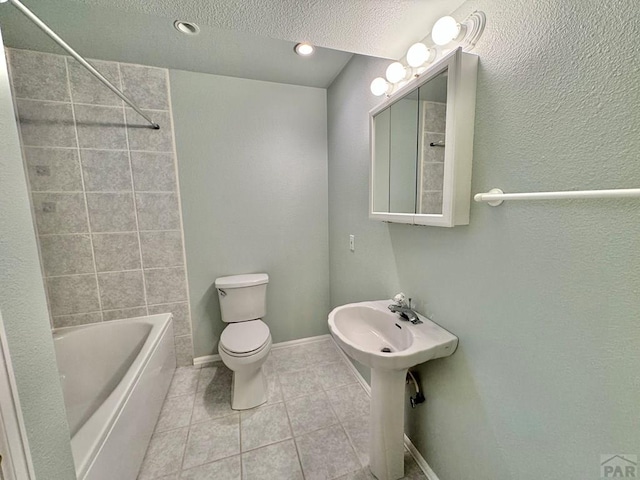 full bath with a textured ceiling, tile patterned flooring, toilet, baseboards, and shower / bathing tub combination